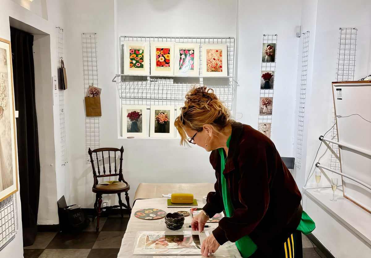 Annika Persson arranging her flower prints on a table in a white gallery room
