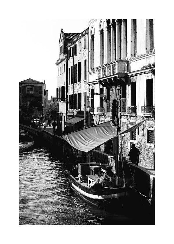 Black and white poster of a boat docked along a canal with historic Venetian buildings in the background.