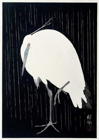 Japanese woodblock print of an egret standing in the rain, by Ohara Koson, on a black background.