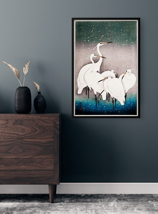 Framed "Group of egrets" poster by Ohara Koson displayed on a dark wall above a wooden dresser.