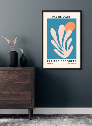 French art inspired plakat with pink abstract shapes on blue, framed and hung above a modern wooden dresser.