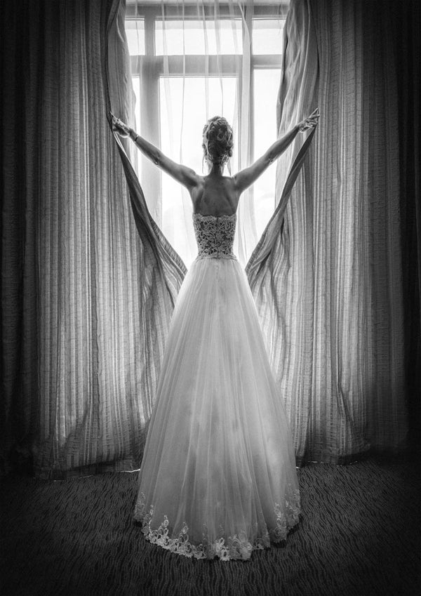A woman in an elegant gown stands before a window, holding open curtains; cover of Girl in Paris by Boris Hristov.