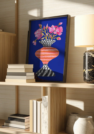 Lush Magnolia by Marjorie Salvagni in a dark frame on a wooden shelf beside books and a lamp