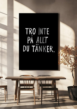 Tro inte på allt du tänker by Grafik bageri hanging above a wooden dining table in warm sunlight