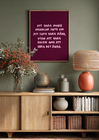 Modig by Grafik bageri above a wooden sideboard on a sage green wall