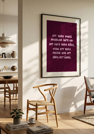 Modig by Grafik bageri in a black frame in a bright dining room with wooden chairs