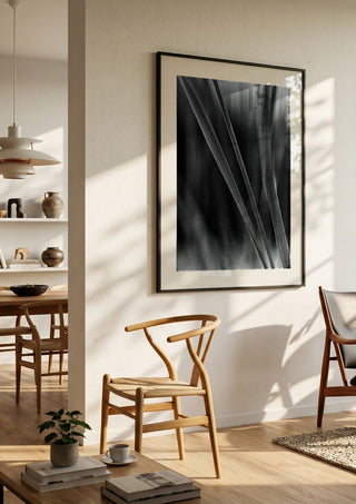 Diagonale Halme by Guido Lucker in a black frame in a bright dining room with wooden chairs