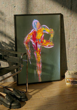 Figure in Motion by René J in a black frame leaning against a concrete wall by a steel chair