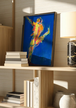 Blue Dancer by René J in a dark frame on a wooden shelf beside books and a lamp
