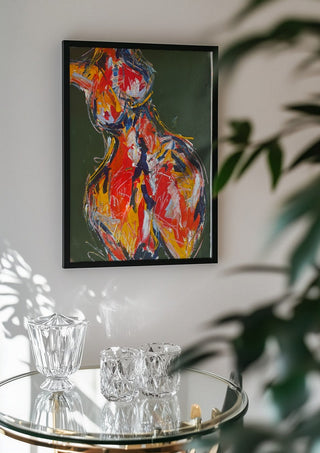 Red Figure by René J in a black frame above a glass table with crystal glassware