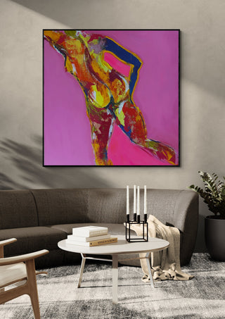 Pink Nude by René J in a black frame above a grey sofa with a round coffee table and candlesticks