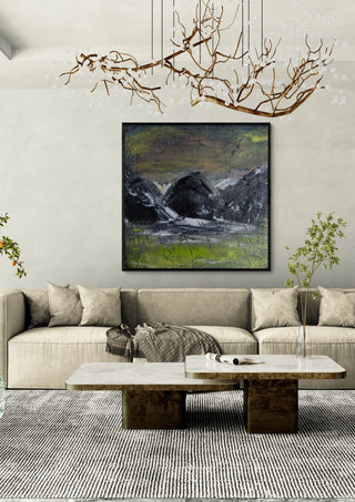 Dark Hills by luco art in a black frame above a beige sofa under a branch chandelier