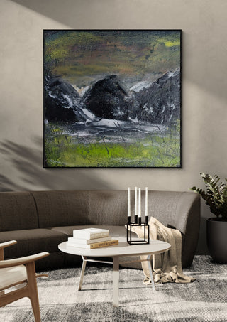 Dark Hills by luco art in a black frame above a grey sofa with a round coffee table and candlesticks