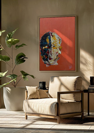 Head in Colour by René J framed above a beige armchair beside a potted plant
