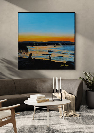 Last Rays by Nella Hajdu in a black frame above a grey sofa with a round coffee table and candlesticks