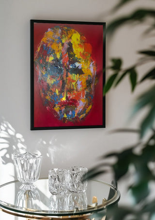 Colour Mask by René J in a black frame above a glass table with crystal glassware