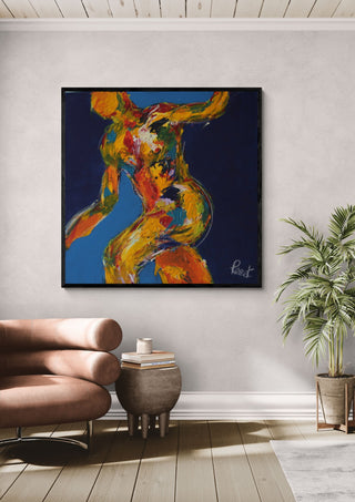 Dancer on Blue by René J in a black frame above a tan leather chair beside a potted plant
