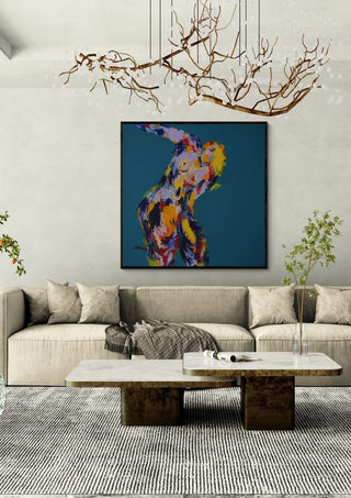 Leaning Back by René J in a black frame above a beige sofa under a branch chandelier
