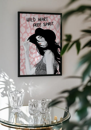 Wild heart, free spirit by Lisen Vennesland in a black frame above a glass table with crystal glassware