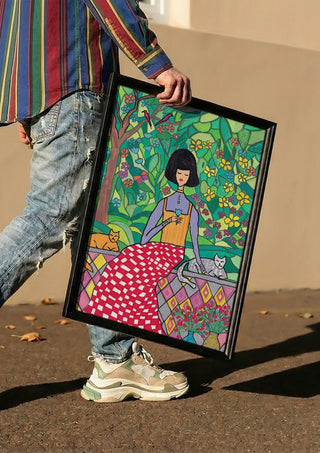 The Garden Wall by Camilla Nilsson carried in a black frame along a sunny street