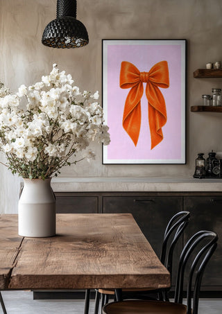 Orange velvet bow on pink by Ohkimiko in a black frame above a rustic table with white flowers