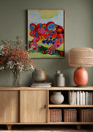 Color frog by Nittaart above a wooden sideboard on a sage green wall