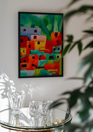 Houses of Favela by Nittaart in a black frame above a glass table with crystal glassware