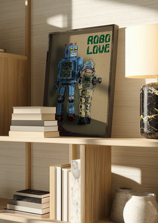 Robo Love by Carl Smith ART in a dark frame on a wooden shelf beside books and a lamp