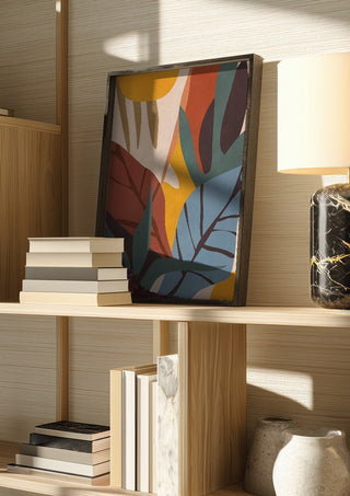 Abstract Art Jungle by ThingDesign in a dark frame on a wooden shelf beside books and a lamp