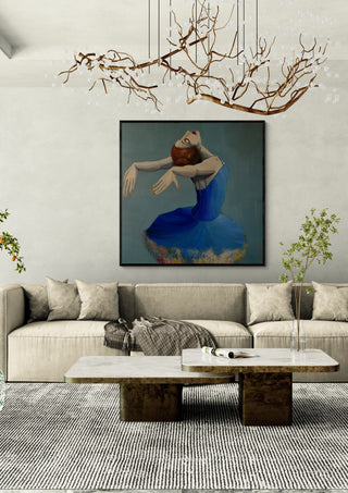 Ballerina in Blue by Justyna Kopania in a black frame above a cream sofa under a branch chandelier