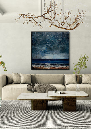 Surf under a Grey Sky by Justyna Kopania in a black frame above a cream sofa under a branch chandelier