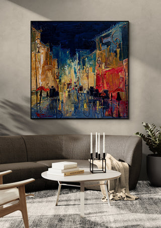 Night Street with Red Umbrellas by Justyna Kopania in a black frame above a dark sofa with candlesticks on a round table