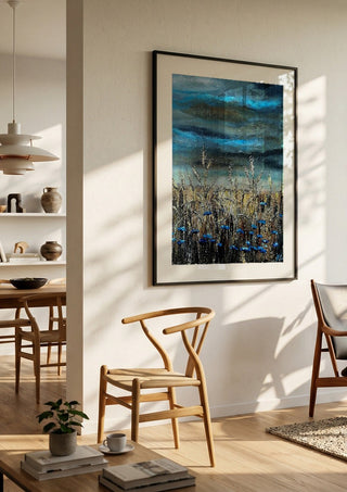 Blue fields by Lüba in a black frame in a bright dining room with wooden chairs