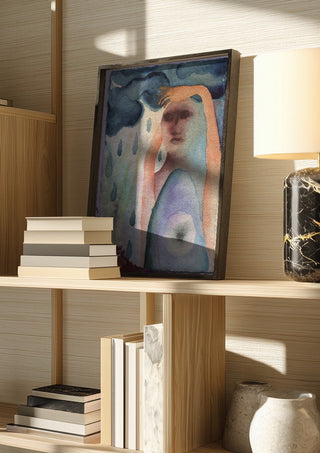 Under the Rain Cloud by Shimmering Ugly in a dark frame on a wooden shelf beside books and a lamp