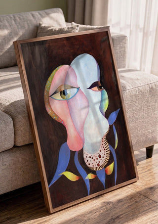 Two Eyes, One Head by Shimmering Ugly in a walnut frame leaning against a grey sofa