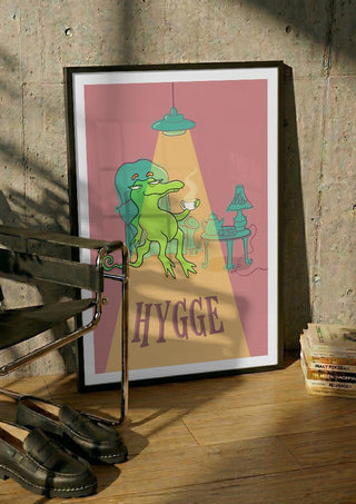 Hygge Crocodile by Elisa Albanelli in a black frame leaning against a concrete wall by a steel chair