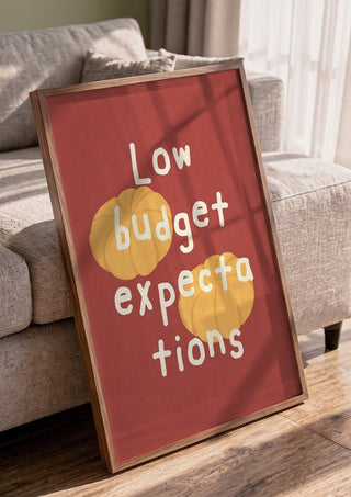Low Budget Expectations by Jakob Falkenberg in a walnut frame leaning against a grey sofa