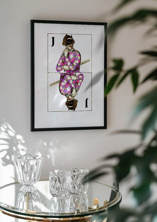 Joker by Bent Hardervig in a black frame above a glass table with crystal glassware