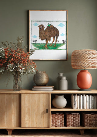 The Camel and the Book by Waldemar Mandzel above a wooden sideboard on a sage green wall