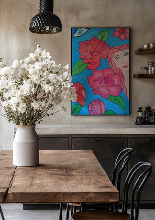 The watching Eye by Carmen Coduri in a black frame above a rustic table with white flowers