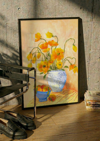 Poppies And Peaches by Deblina Dey in a black frame leaning against a concrete wall by a steel chair