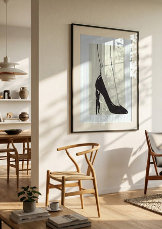 Heavy is the Heel by Nari in a black frame in a bright dining room with wooden chairs