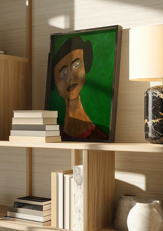 Sinthea by Ian Frederick Harris in a dark frame on a wooden shelf beside books and a lamp