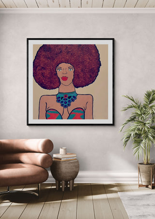 Afrocentric Radiance by Bibi in a black frame above a pink armchair beside a palm