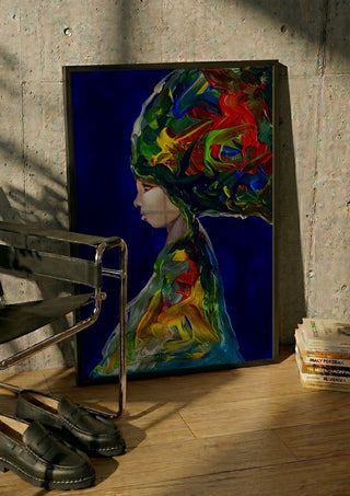 The Wind by Ronny Simon in a black frame leaning against a concrete wall by a steel chair