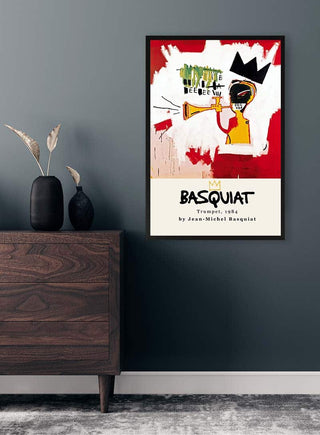 Framed "Trumpet" by Jean Michel Basquiat on a wall above a wooden sideboard with vases.