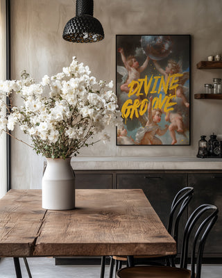 A poster for Divine Groove - Dikhotomy with cherubs and bold yellow text hangs in a stylish dining room.