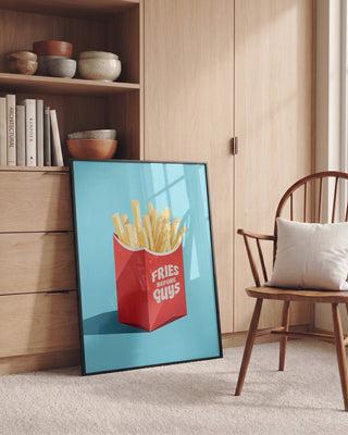 Framed "Fries Before Guys" print by Andreas Magnusson resting against a wall in a cozy, modern room.