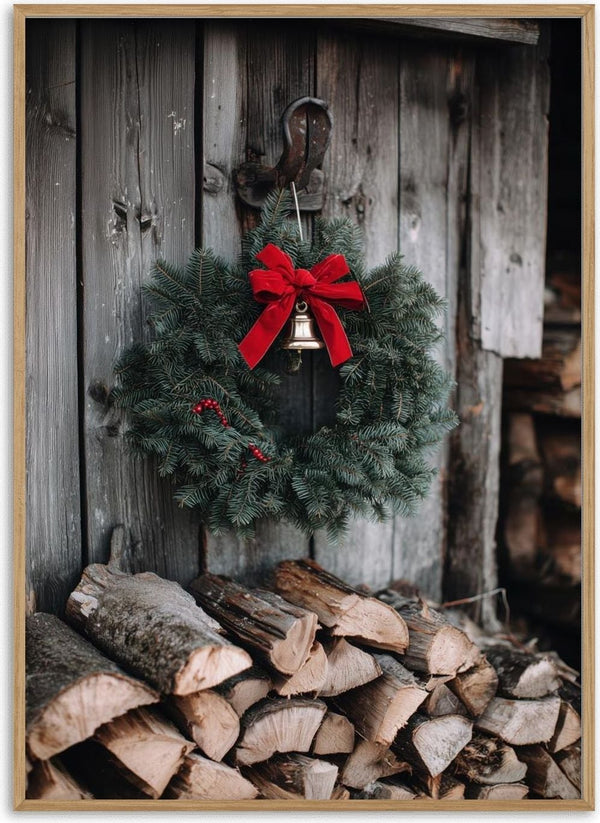 Christmas wreath with a red bow and bell hanging on a rustic wooden wall above stacked firewood.
