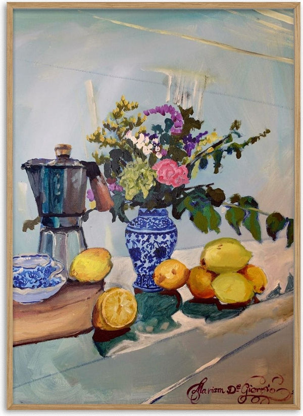 Morning coffee by Mariam De Giorgio — a steel espresso pot, lemons and a blue-and-white vase of flowers on a pale table.
